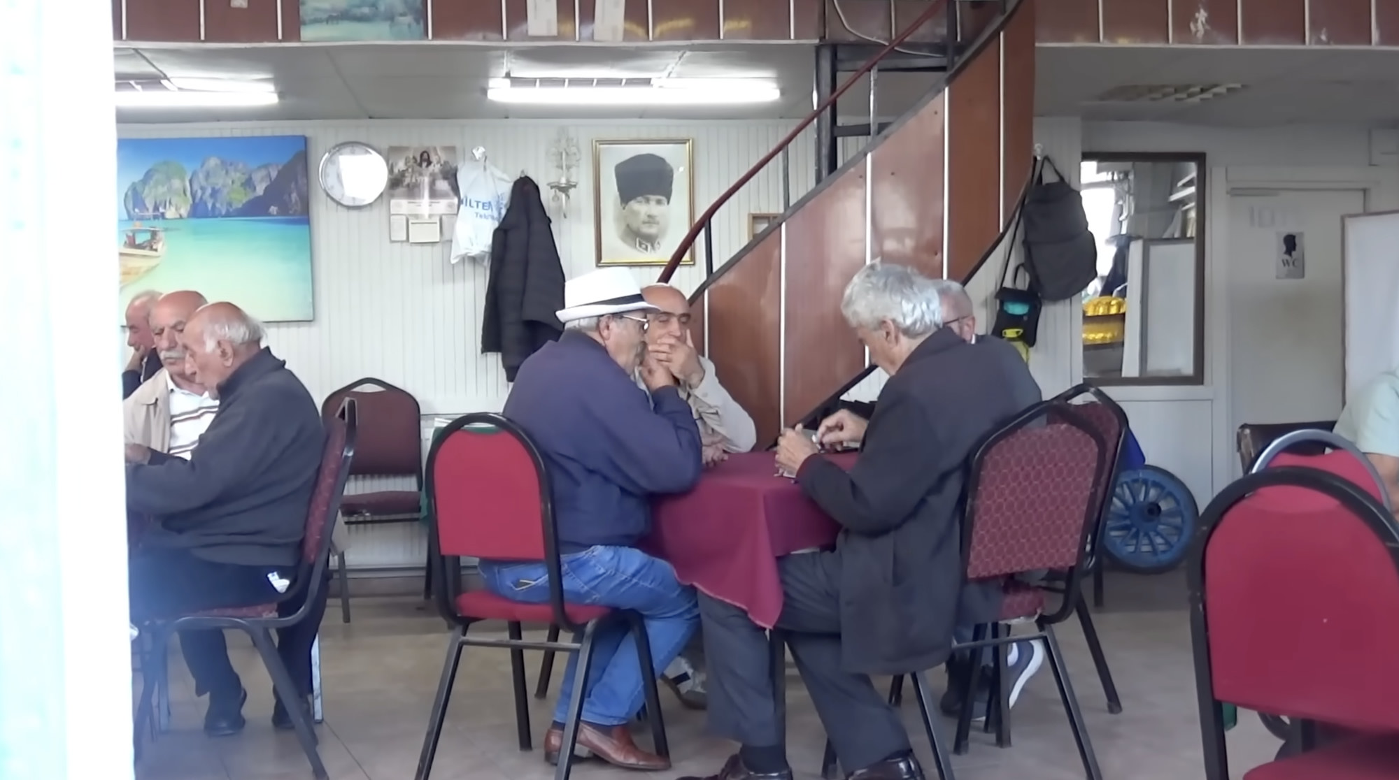 Older men sitting around tables in a small cafe