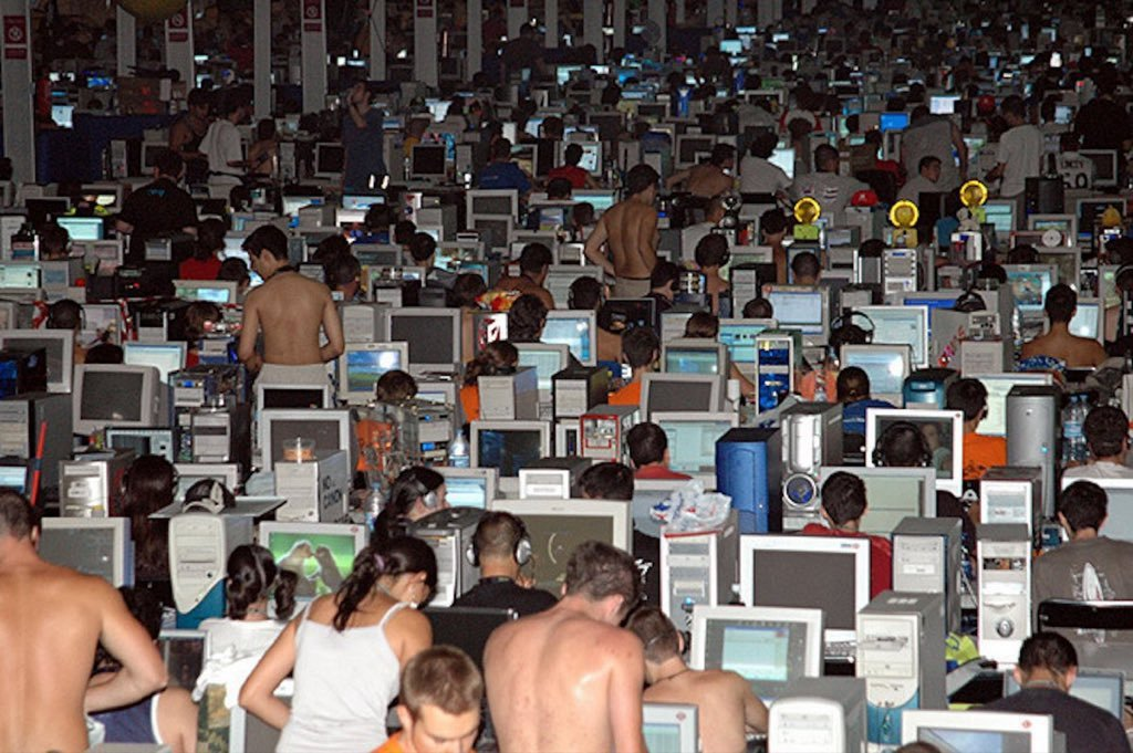 Crowded computer lab filled with people and glowing monitors