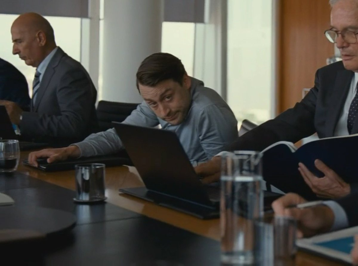 Person slumped over a laptop during a business meeting