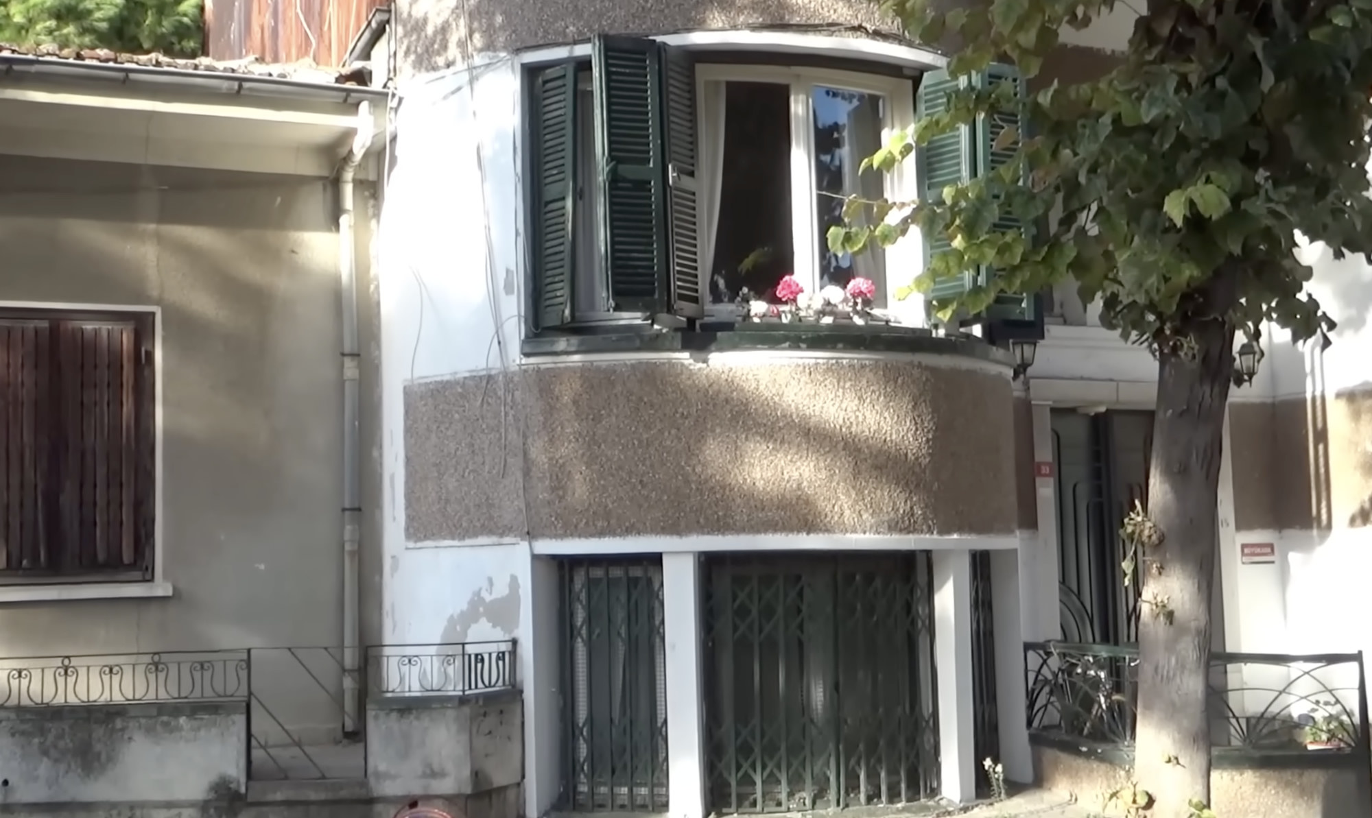 Upper window with green shutters and flowers on the ledge