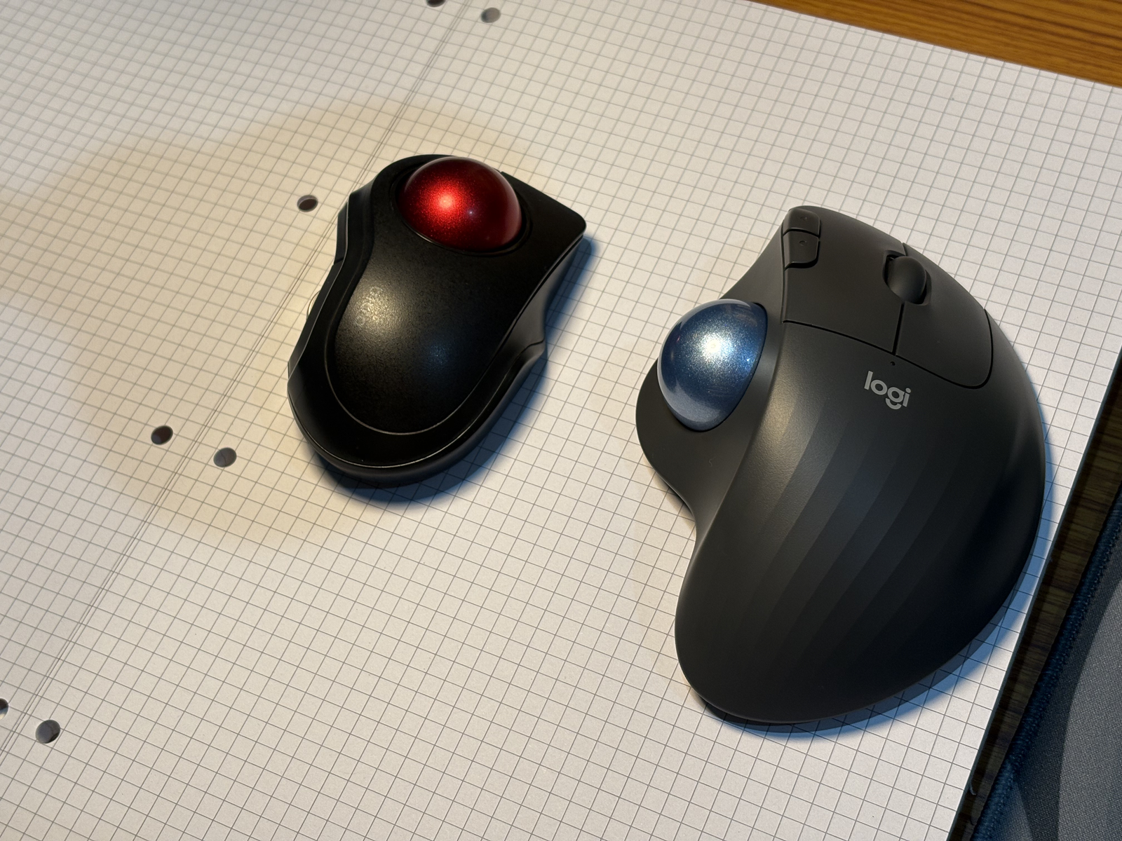 An Elecom Bitra finger trackball and a Logitech Ergo M575s thumb trackball resting side by side on graph paper.